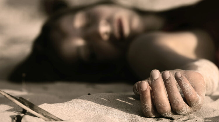 woman playing dead, lying in the sand