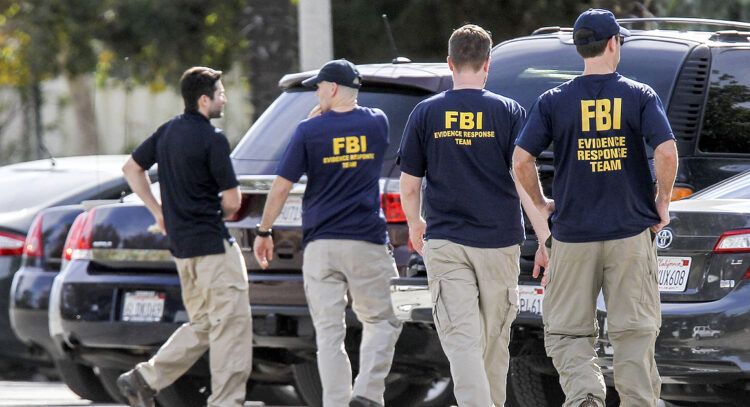 FBI agents search outside a home in connection to Wednesday's shootings in San Bernardino, Thursday, Dec. 3, 2015, in Redlands, Calif. A heavily armed man and woman opened fire Wednesday on a holiday banquet for his co-workers, killing multiple people and seriously wounding others in a precision assault, authorities said. Hours later, they died in a shootout with police. (AP Photo/Ringo H.W. Chiu)